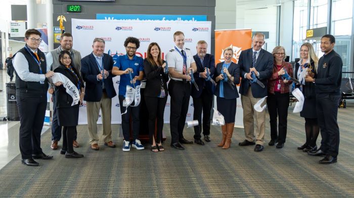 Row of 12 people cutting a ribbon for an airline launch.